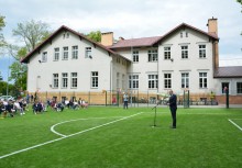 Burmistrz Gminy Żukowo przemawia na nowym boisku, w tle szkoła - powiększ