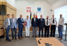 9 osób w sali Rady Miejskiej w Urzędzie Gminy w Żukowie. Burmistrz trzyma teczkę z umową - powiększ