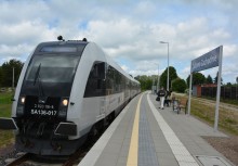 Nowoczesny pociąg pasażerski zatrzymany na peronie stacji „Żukowo Zachodnie”. Na peronie widoczni pasażerowie oraz tablica z nazwą przystanku. 