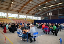Sala sportowa na której rozstawione są stoliki przy których grają w karty po 4 osoby - powiększ