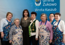 Zdjęcie grupowe kobiet na tle baneru 'Gmina Żukowo - Wrota Kaszub'. - powiększ