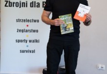 Na zdjęciu widać mężczyznę, który trzyma w dłoniach ulotki. W tle widać baner z logo 'WKS Zbrojni dla RP'.  - powiększ