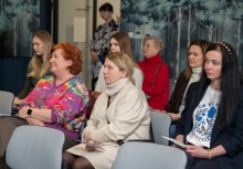 Grupa osób siedząca na krzesełkach w sali - powiększ