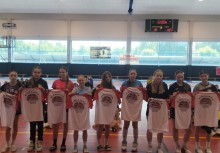 Zawodniczki wyróżnione w turnieju prezentują pamiątkowe koszulki z nadrukiem „Mistrzostwa Polski” – stoją w szeregu na hali sportowej podczas oficjalnej ceremonii.  - powiększ