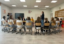 Uczniowie siedzą w półkolu podczas Wojewódzkiego Konkursu Wiedzy o Pszczołach. W tle widać komisję. 