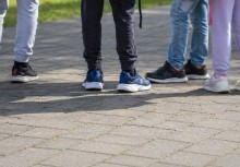Na zdjęciu  grupa dzieci stojąca na chodniku - widoczne są tylko ich nogi.  - powiększ