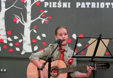 Dziewczynka przy mikrofonie oraz grająca na gitarze podczas konkursu - powiększ