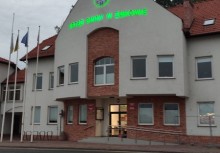 Część budynku Urzędu Gminy w Żukowie. Herb i napis 'Gmina Żukowo' są podświetlone na zielono. - powiększ