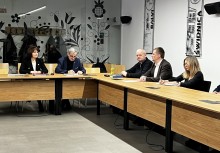 Pięć osób siedzących przy stołach. Mężczyzna i kobieta notują.   - powiększ