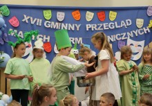 Dzieci na scenie podczas występu. W tle dekoracja z napisem 'XVII Gminny Przegląd Małych Form Scenicznych'.