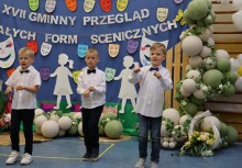 Trzech chłopców podczas występu. W tle widać ściankę dekoracyjną. - powiększ