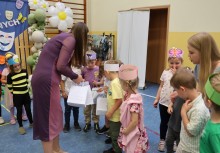 Kobieta wręcza dzieciom paczki upominkowe. - powiększ