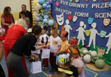 Dorośli wręczają dzieciom paczki upominkowe.  - powiększ