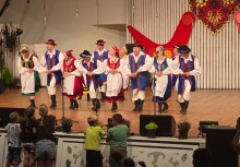 Zespół kaszubski trzymający się za ręce, tańczący na scenie. - powiększ