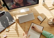 spotkanie online, osoba przy komputerze notuje w notesie - powiększ