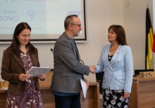 Po lewej stronie kobieta trzyma dokumenty. Po prawej Burmistrz Gminy Żukowo i mężczyzna podają sobie rękę.  - powiększ