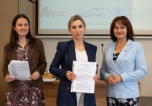 Trzy kobiety. Kobieta po środku trzyma dokument.  - powiększ