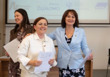 Trzy uśmiechnięte kobiety trzymające dokumenty. - powiększ