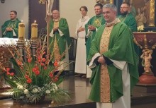 Kapłani w zielonych ornatach stoją przy ołtarzu podczas uroczystości kościelnej; na pierwszym planie widoczna kompozycja kwiatowa.








 - powiększ
