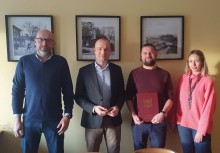 4 osoby, jedna z nich trzyma teczkę z umową