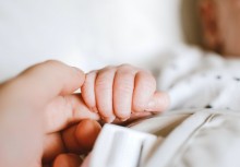 Dłoń niemowlęcia chwyta palec dłoni dorosłej osoby