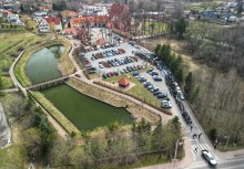 Zdjęcie z drona, na którym widać ludzi podczas przejścia z kościoła na cmentarz. W tle kościół - powiększ