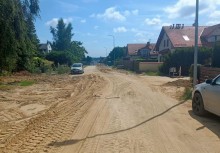 piaszczysta ulica, z prawej i w centrum zaparkowane samochody