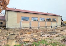 Na zdjęciu widać budynek szkoły podczas rozbudowy. Widoczne są prace ziemne  - powiększ