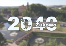 Na pierwszym planie logo '2040 Żukowo'. W tle rozmyte zdjęcie na którym z góry widać kościół pw. W.N.M.P w Żukowie 