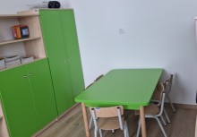 Sala przedszkolna, szafy i zielone szafki, stół i krzesełko