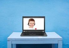 [zdjęcie poglądowe ze strony pixabay.com] Na stole stoi laptop. Na ekranie laptopa widać panią w słuchawkach. - powiększ