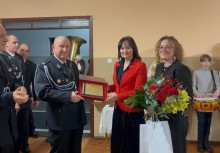 Burmistrz Mariola Zmudzińska wręcza list gratulacyjny Prezesowi OSP Franciszkowi Bisewskiemu, obok z kwiatami Przewodnicząca Rady Miejskiej Katarzyna Cichowicz - powiększ
