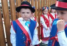 Chłopcy i dziewczynki z przedszkola w Miszewie w tradycyjnych kaszubskich strojach ludowych – dzieci czekają na występ z okazji Święta Konstytucji 3 Maja, stojąc przy drewnianym ogrodzeniu. - powiększ