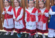 Cztery dziewczynki z przedszkola w Miszewie w tradycyjnych kaszubskich strojach – ubrane w czerwone gorsety i białe fartuszki z haftem, czekają na występ podczas obchodów Święta Konstytucji 3 Maja. - powiększ