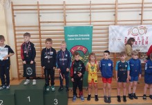 Młodzi zawodnicy na podium oraz obok niego – dekoracja medalowa podczas zawodów sportowych organizowanych przez Pomorskie Zrzeszenie LZS. - powiększ