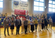 Uroczystość w hali sportowej – wręczenie nagród dla nauczycieli lub wychowawców. W tle baner „Gmina Żukowo”, napis „Gminny Konkurs Wiedzy o Młodzieży i Środowisku”. - powiększ