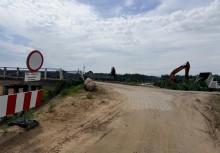 Piaszczysta droga oraz wiadukt. Po lewej stronie zna zakazu ruchu. W tle widać koparkę oraz drzewa. - powiększ