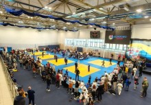 Na pierwszym planie mata na której są zawodnicy, wokół widownia - powiększ