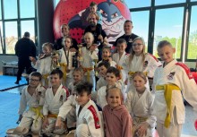 Grupa dzieci w strojach do judo oraz troje dorosłych. - powiększ