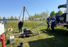 Trzech mężczyzn pracujących na trawiastym terenie przy urządzeniach technicznych. - powiększ